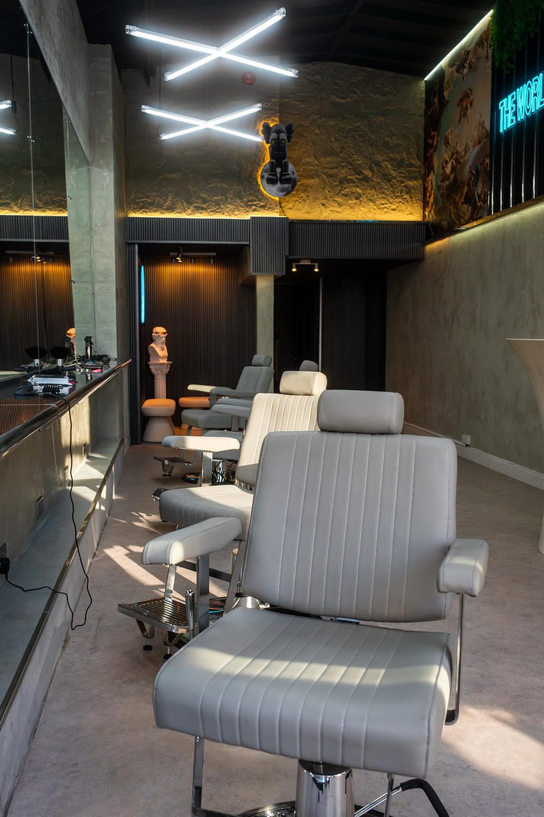The main floor at Culture Box: white leather barber chairs on chrome bases along a mirrored counter, under crossed strip lights.